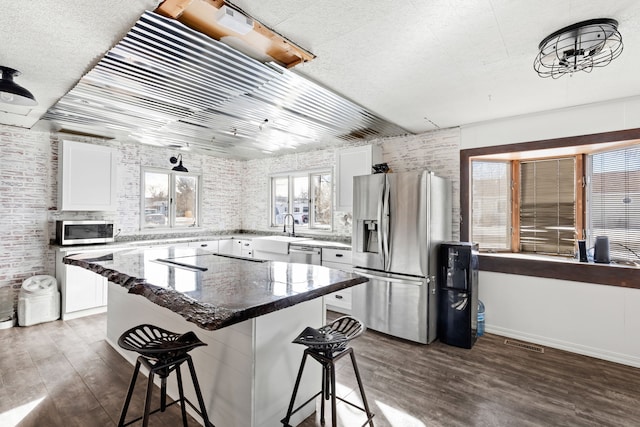 kitchen with a kitchen island, a breakfast bar area, white cabinets, and appliances with stainless steel finishes