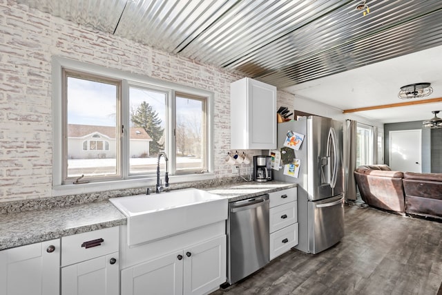 kitchen featuring white cabinetry, brick wall, stainless steel appliances, and sink