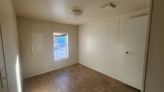 empty room featuring electric panel and a textured ceiling