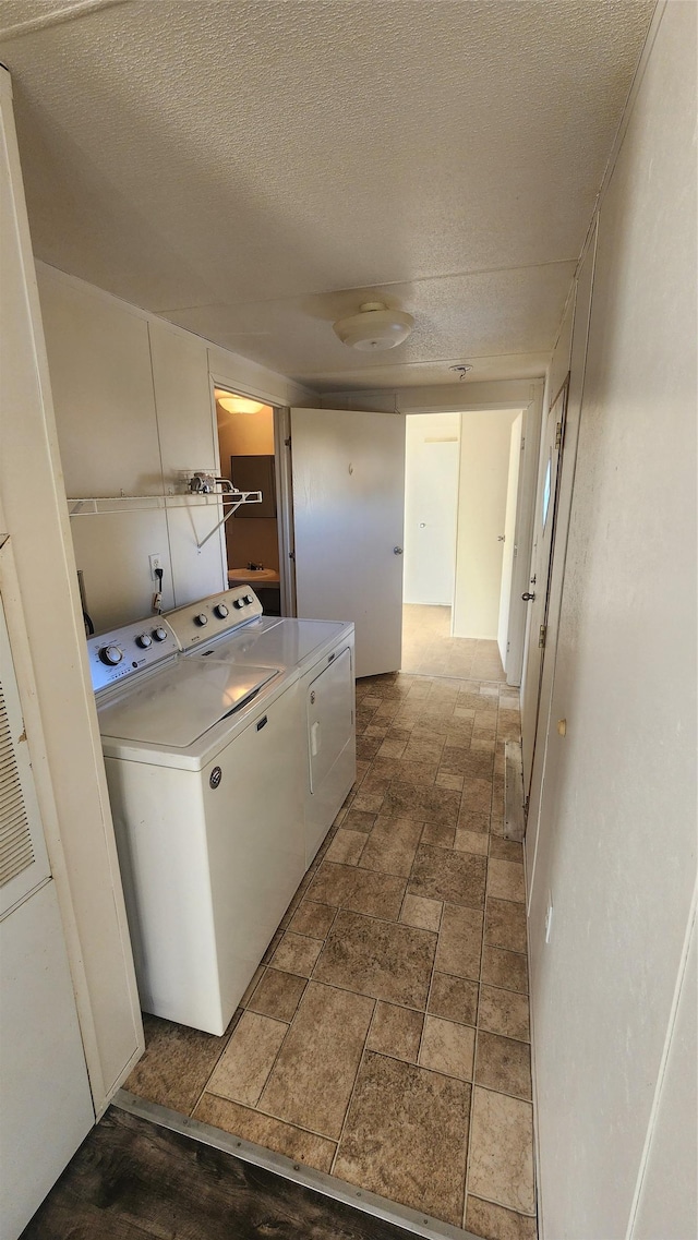 clothes washing area with washing machine and dryer and a textured ceiling