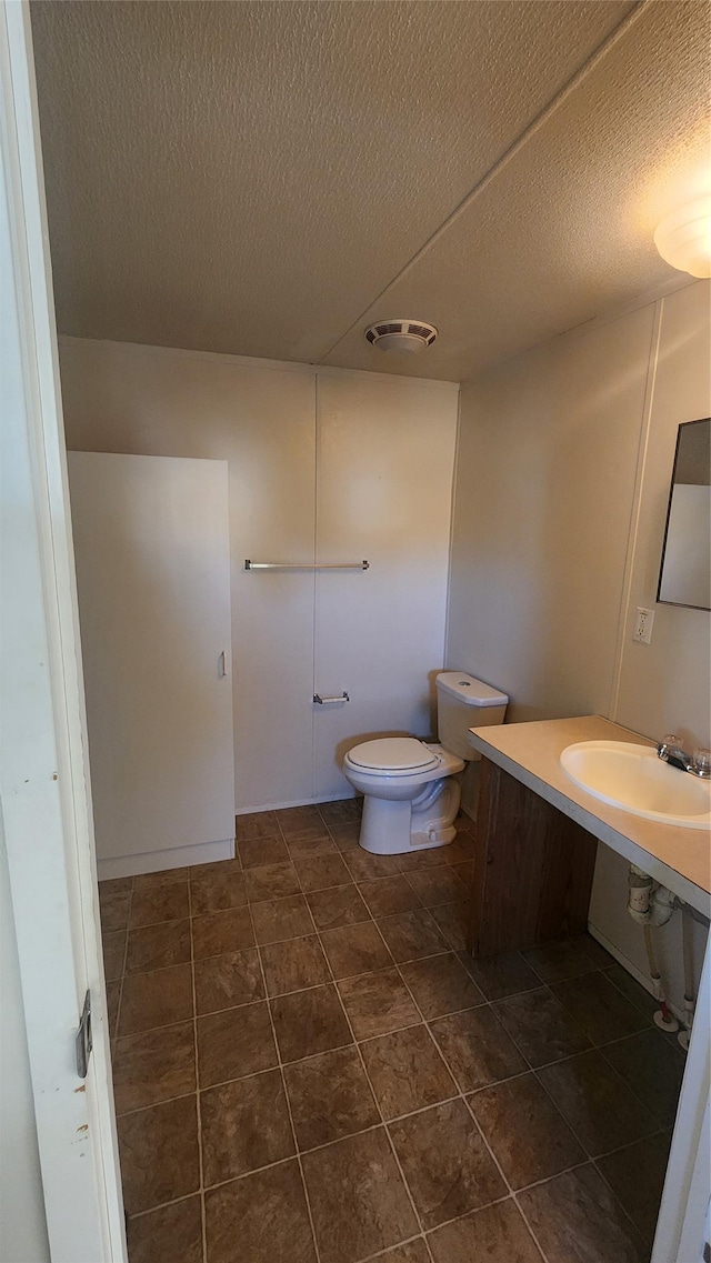 bathroom featuring tile patterned flooring, sink, a textured ceiling, and toilet