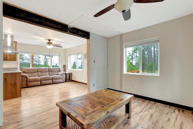 living room with ceiling fan, beam ceiling, and light hardwood / wood-style flooring