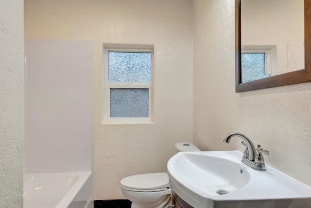 bathroom featuring sink, a bath, and toilet