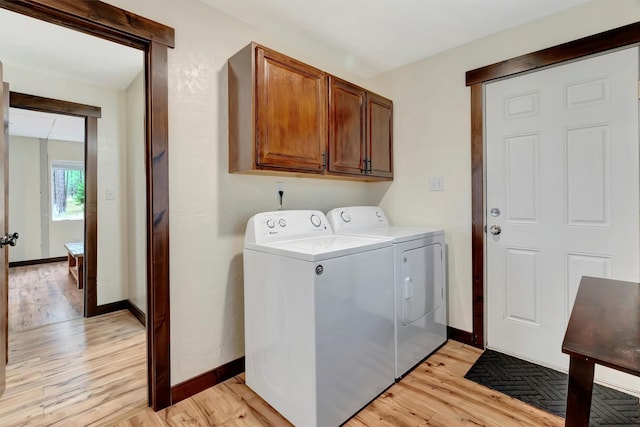 laundry room featuring cabinets, light wood-type flooring, and independent washer and dryer