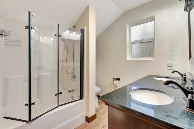 full bathroom featuring lofted ceiling, hardwood / wood-style flooring, bath / shower combo with glass door, vanity, and toilet