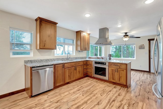 kitchen with sink, light hardwood / wood-style flooring, appliances with stainless steel finishes, island exhaust hood, and kitchen peninsula