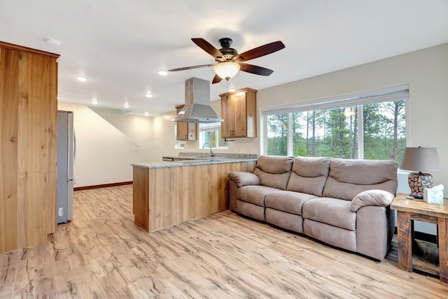 living room featuring ceiling fan, sink, and light wood-type flooring