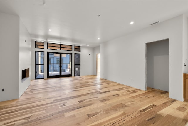 unfurnished living room with light wood-type flooring and french doors