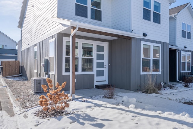 exterior space with central AC unit, fence, and board and batten siding