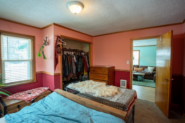 bedroom with crown molding, a closet, a textured ceiling, and a spacious closet