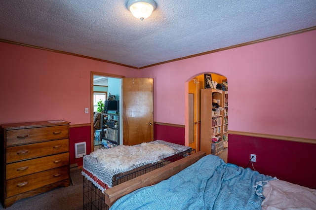 bedroom featuring crown molding, a textured ceiling, and dark colored carpet