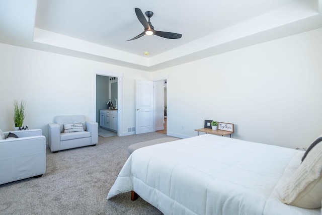 bedroom with ceiling fan, light colored carpet, and a raised ceiling