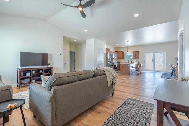 living room with ceiling fan, lofted ceiling, and light hardwood / wood-style floors