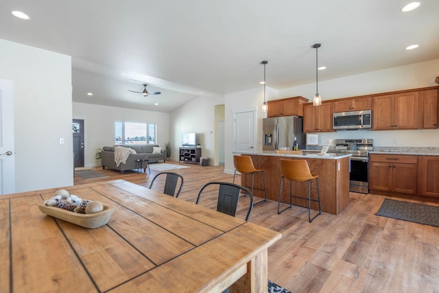 dining space with ceiling fan, lofted ceiling, and light hardwood / wood-style flooring