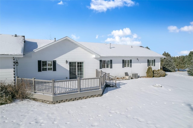 snow covered house featuring central AC unit and a wooden deck