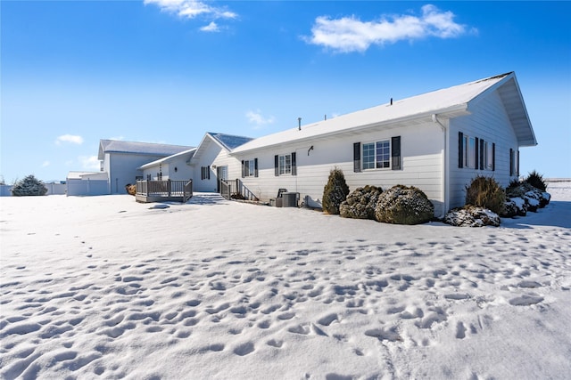 snow covered back of property featuring central AC