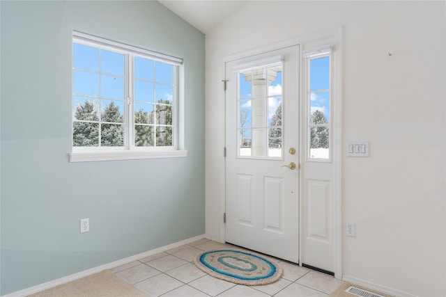 foyer entrance with lofted ceiling, light tile patterned floors, and a wealth of natural light