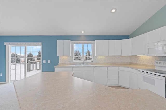 kitchen with tasteful backsplash, white appliances, lofted ceiling, and white cabinets