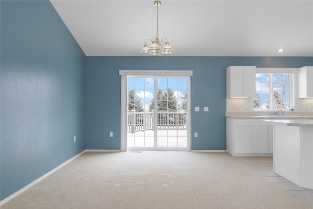 unfurnished dining area with sink, light carpet, and a chandelier