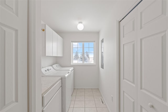 laundry room with cabinets, washing machine and dryer, and light tile patterned floors