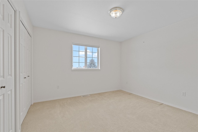 unfurnished bedroom with light carpet and a closet