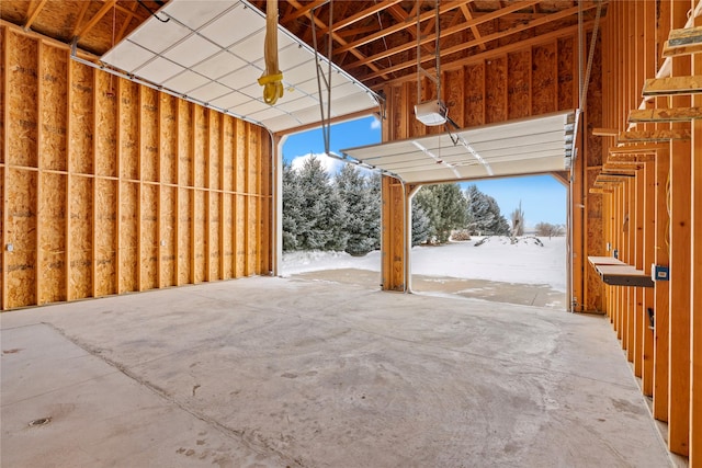 snow covered garage featuring a garage door opener