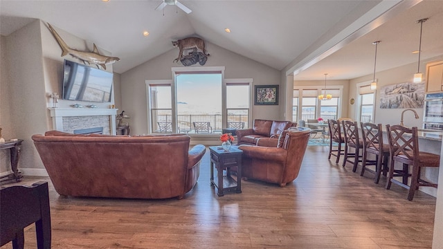 living room with a stone fireplace, dark hardwood / wood-style floors, lofted ceiling, and ceiling fan