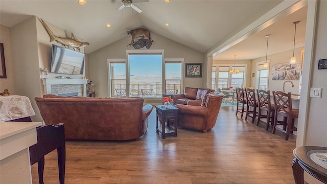 living room featuring hardwood / wood-style flooring, vaulted ceiling, ceiling fan, and a fireplace