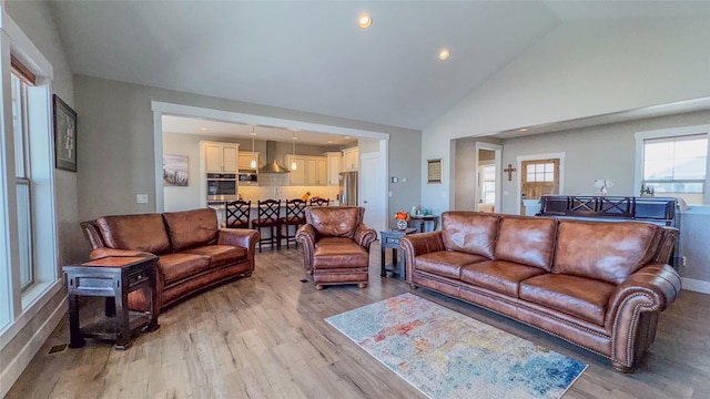 living room featuring high vaulted ceiling and light hardwood / wood-style floors