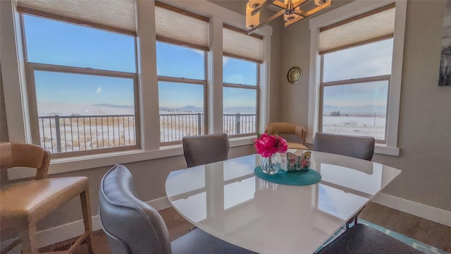 dining space featuring wood-type flooring, a water view, a wealth of natural light, and a notable chandelier