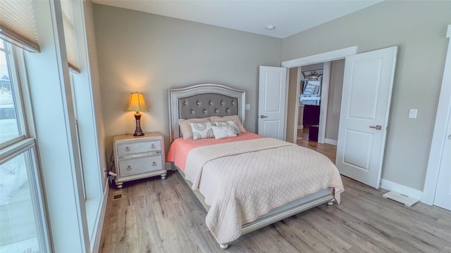 bedroom with multiple windows and light hardwood / wood-style flooring