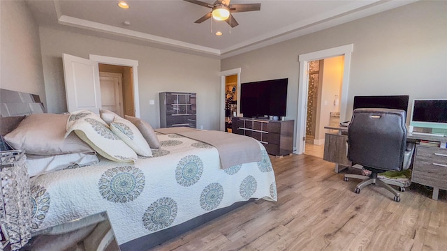 bedroom featuring connected bathroom, light hardwood / wood-style flooring, and a raised ceiling