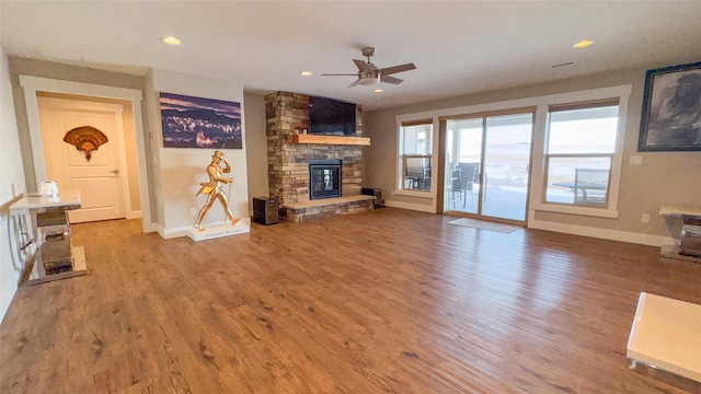 living room featuring hardwood / wood-style flooring, a stone fireplace, and ceiling fan