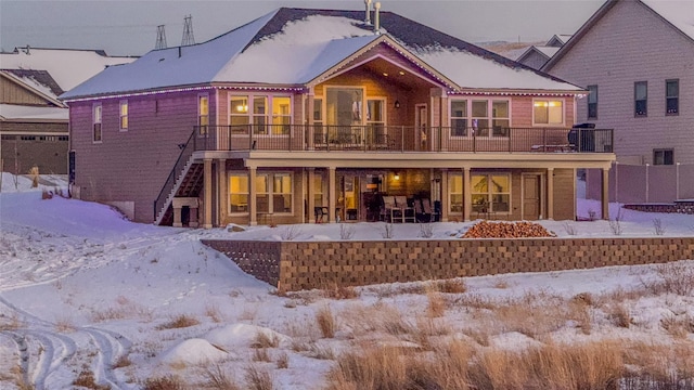 snow covered house featuring a balcony