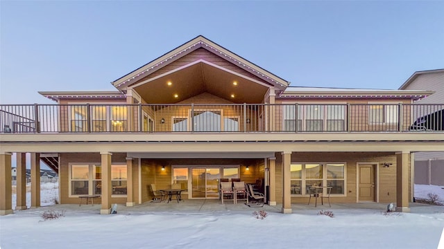 snow covered back of property featuring a balcony