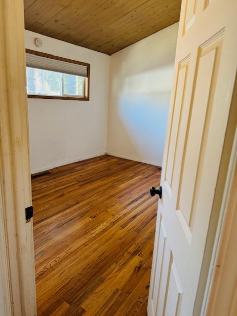 spare room featuring wood ceiling and wood-type flooring