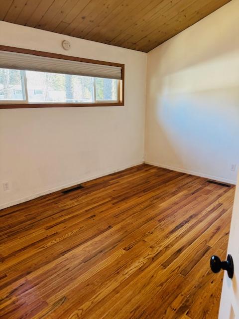 empty room featuring hardwood / wood-style floors and wooden ceiling