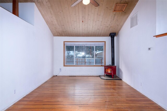 unfurnished living room featuring lofted ceiling with beams, a wood stove, wood ceiling, ceiling fan, and light hardwood / wood-style flooring