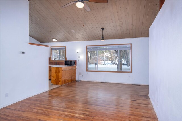 unfurnished room featuring hardwood / wood-style flooring, wooden ceiling, and a wood stove