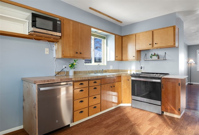 kitchen with stainless steel appliances, hardwood / wood-style flooring, sink, and kitchen peninsula