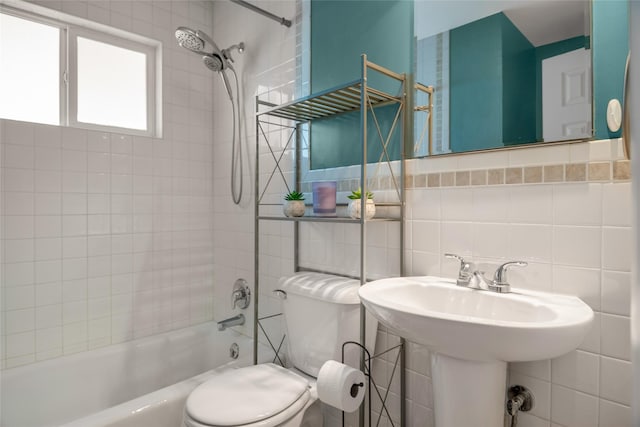 bathroom featuring tile walls, tiled shower / bath, and toilet