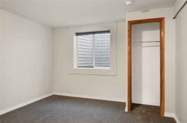 unfurnished bedroom featuring dark carpet and a closet