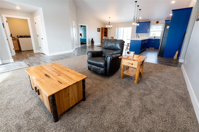 living room featuring lofted ceiling, sink, dark hardwood / wood-style flooring, and a chandelier