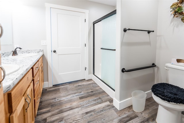 bathroom featuring vanity, a shower with shower door, hardwood / wood-style floors, and toilet