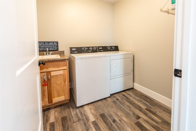 laundry room featuring sink, dark wood-type flooring, washer and clothes dryer, and cabinets