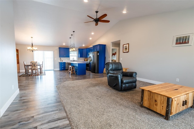 living room with sink, dark wood-type flooring, ceiling fan with notable chandelier, and high vaulted ceiling