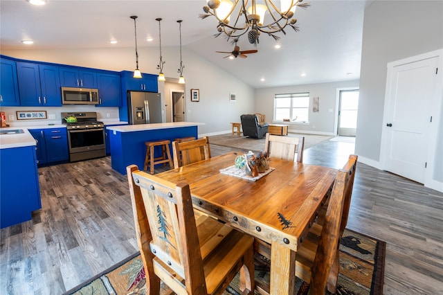 dining area featuring ceiling fan with notable chandelier, sink, dark hardwood / wood-style floors, and vaulted ceiling