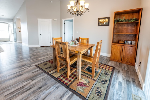 dining area featuring dark wood-type flooring, an inviting chandelier, and a high ceiling