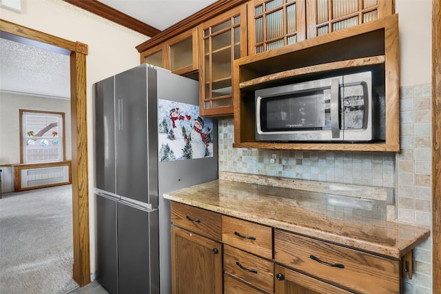 kitchen featuring appliances with stainless steel finishes, light stone counters, a textured ceiling, decorative backsplash, and light colored carpet