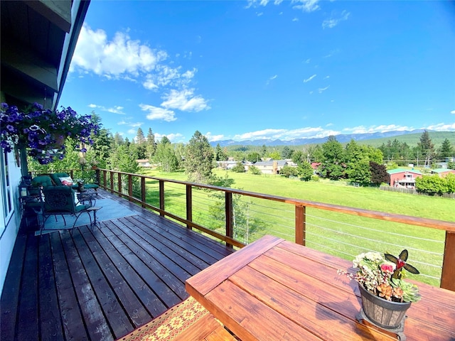 wooden deck with a mountain view and a yard